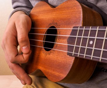 Closeup of young man hands playing concert ukulele